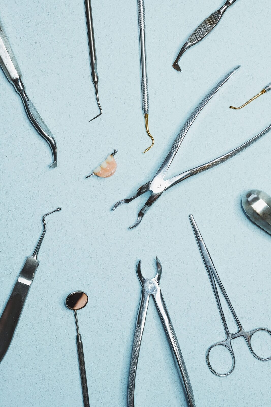 Collection d'instruments dentaires d'extraction disposés en plateau, dont daviers